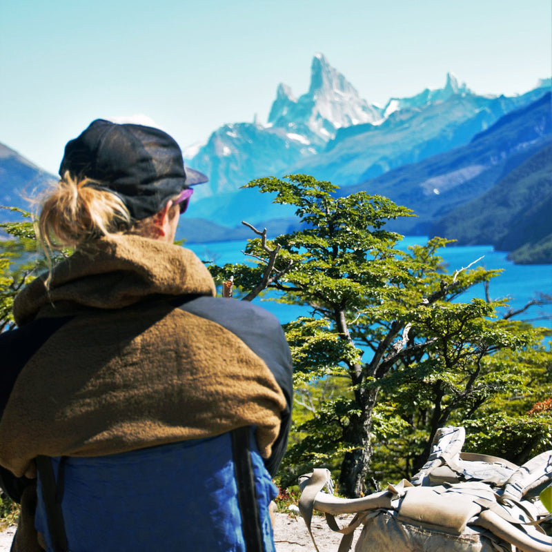 Load image into Gallery viewer, A person looking out over a blue lake and pointy mountains