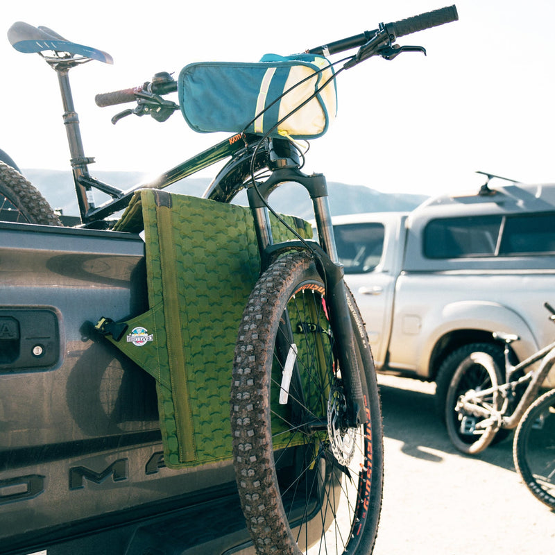 Load image into Gallery viewer, Hex 2.0 Crazy Creek chair being used as a tailgate pad for a mountain bike on a truck