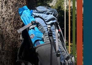 Blue air chair is rolled up compactly and placed in a backpack water bottle holder
