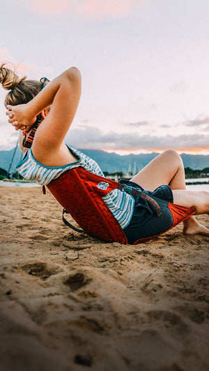 Woman lounging on the beach in front of the sunset