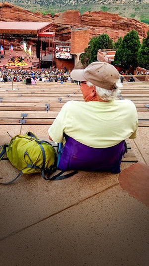 Man sitting at a concert at red rocks music venue in his crazy creek chair with back support