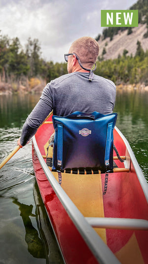 Man paddling in a canoe sitting in a canoe IV paddle chair on a green lake in the mountains