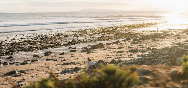Wide shot of the beach and a man lounging in a chair during sunset
