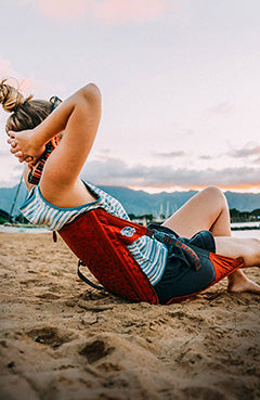 Woman lounging on the beach in front of the sunset