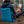 Man sitting in a comfortable blue inflatable chair in front of a campfire