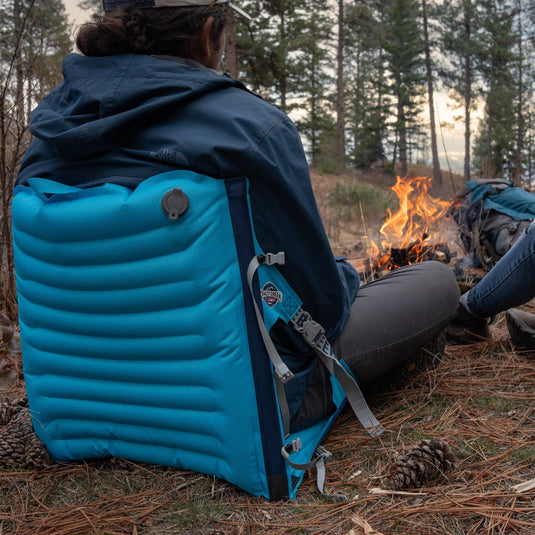 Man sitting in a comfortable blue inflatable chair in front of a campfire