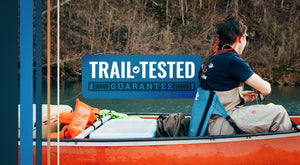 Trail Tested Guarantee - Man fishing off a red canoe while sitting in a chair with back support