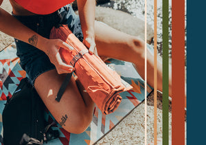 a woman is rolling up the hex 2.0 crazy creek chair into a packable 4 inch roll. 