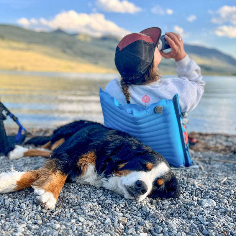 Load image into Gallery viewer, Woman and her dog lounging on the edge of a lake while sitting in a comfy inflatable camping chair
