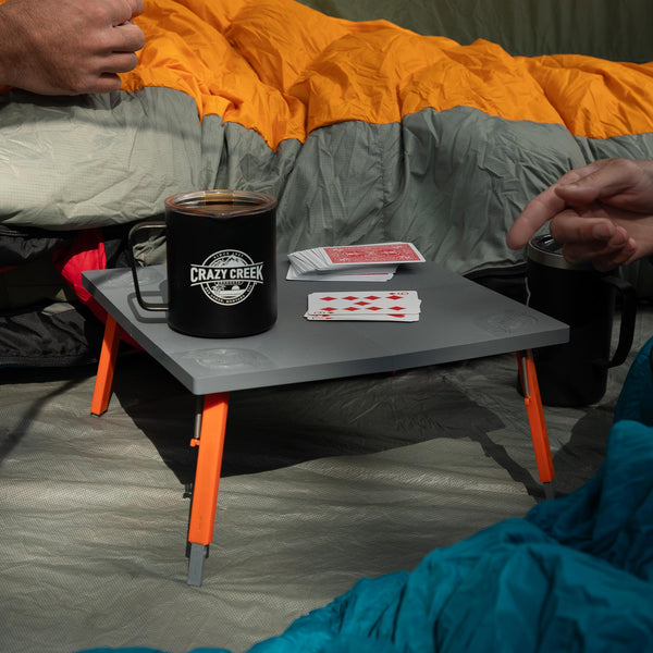 Two people playing cards in a tent on the crazy creek foldable table