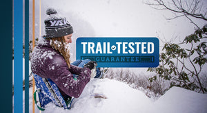 Trail Tested Guarantee - Woman sitting in the snow in her blue chair on the edge of a mountain