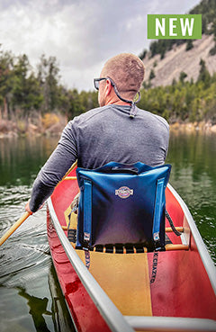 Man paddling in a canoe sitting in a canoe IV paddle chair on a green lake in the mountains