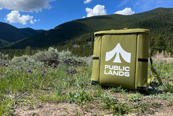 A custom Crazy Creek chair with Public Lands printed on it sitting in front of a beautiful hillside