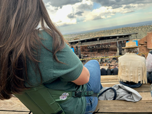 Woman leaning back in a green Crazy Creek Original Chair, enjoying a relaxed outdoor setting.