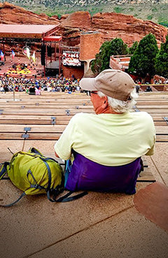 Man sitting at a concert at red rocks music venue in his crazy creek chair with back support