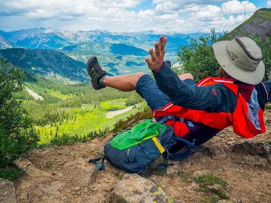 Man reclining on a Crazy Creek HEX 2.0 Original Chair, relaxing in a mountainous setting.